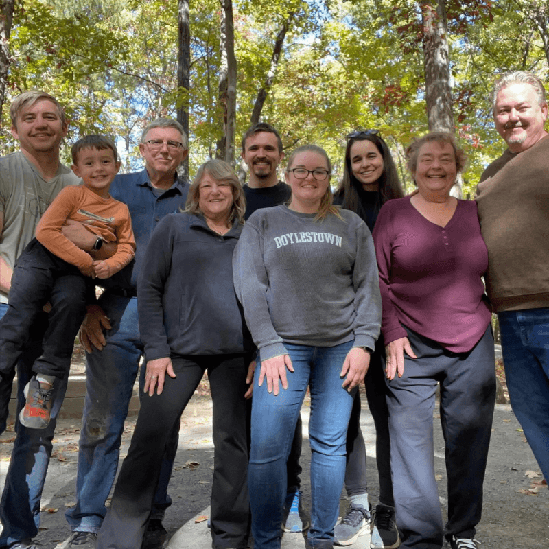 The Daniels' family smiles at the camera in a woodland setting